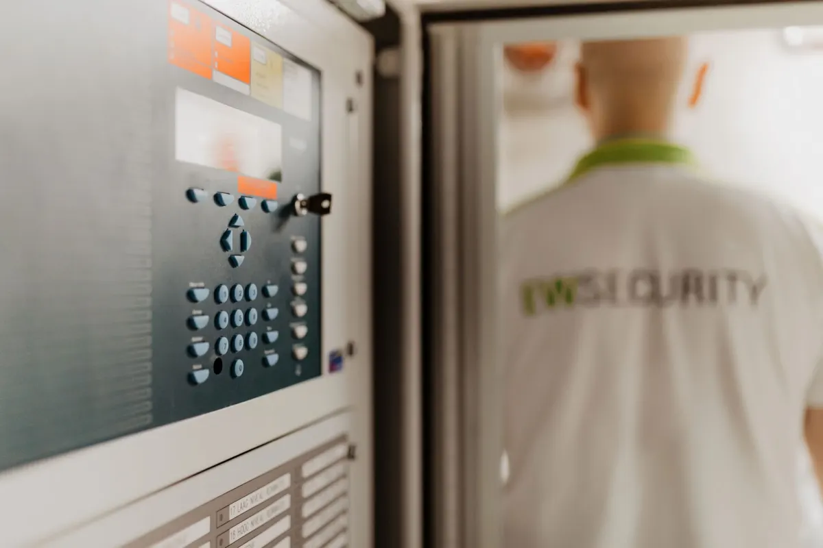 Brandmeldcentrale met EW Security-medewerker op de achtergrond