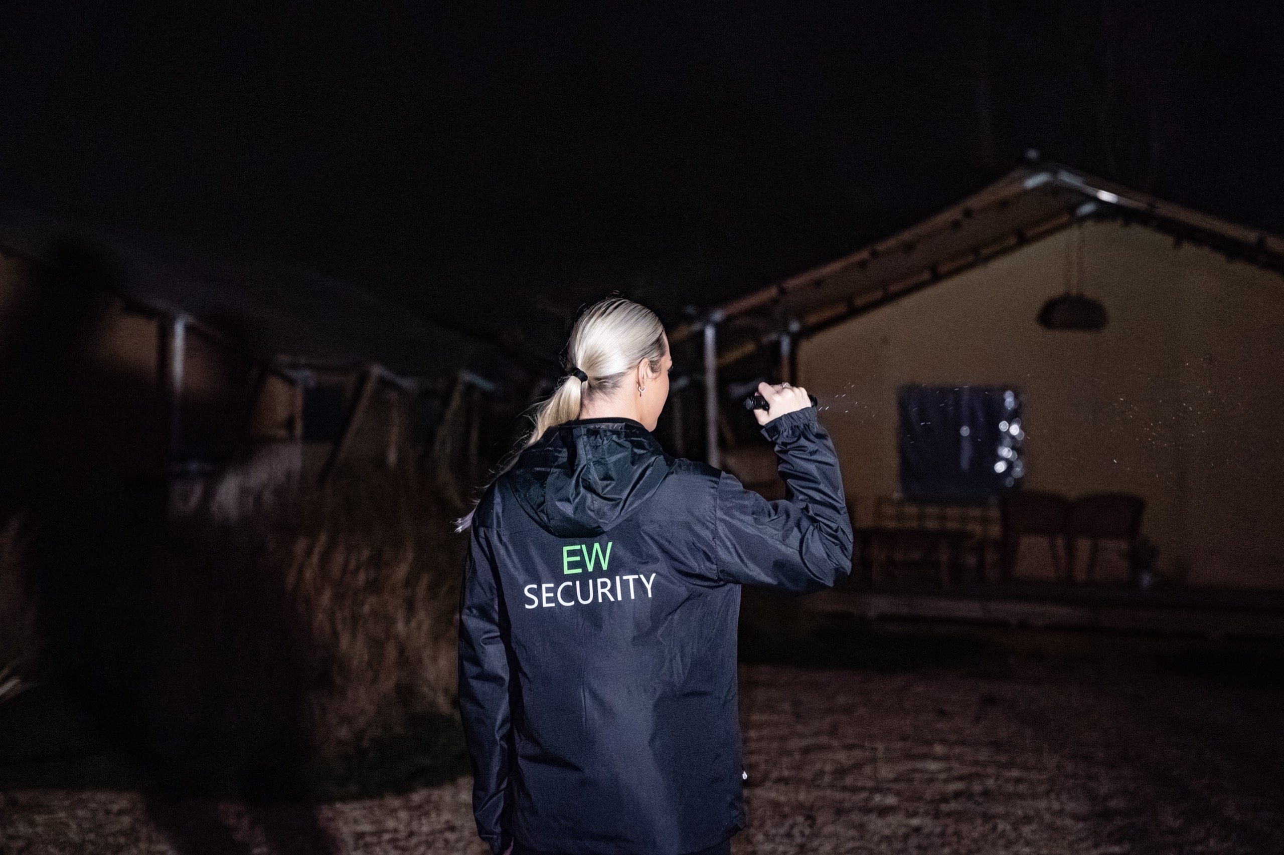 Beveiliger schijnt met zaklamp op een safaritent tijdens een nachtcontrole