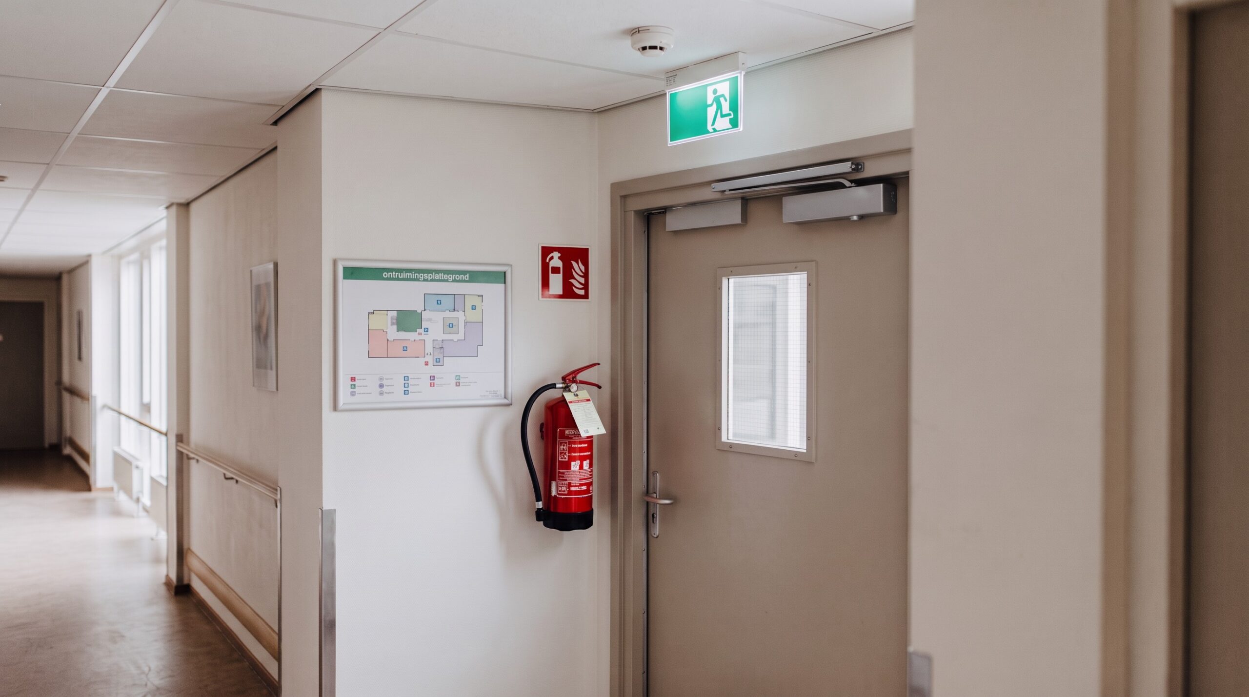 AI-beeld van EW Security: branddeur, rookmelder en blusser in een zorggang